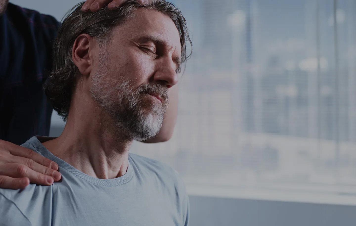 Man receiving chiropractic shoulder adjustment from healthcare provider's hands.